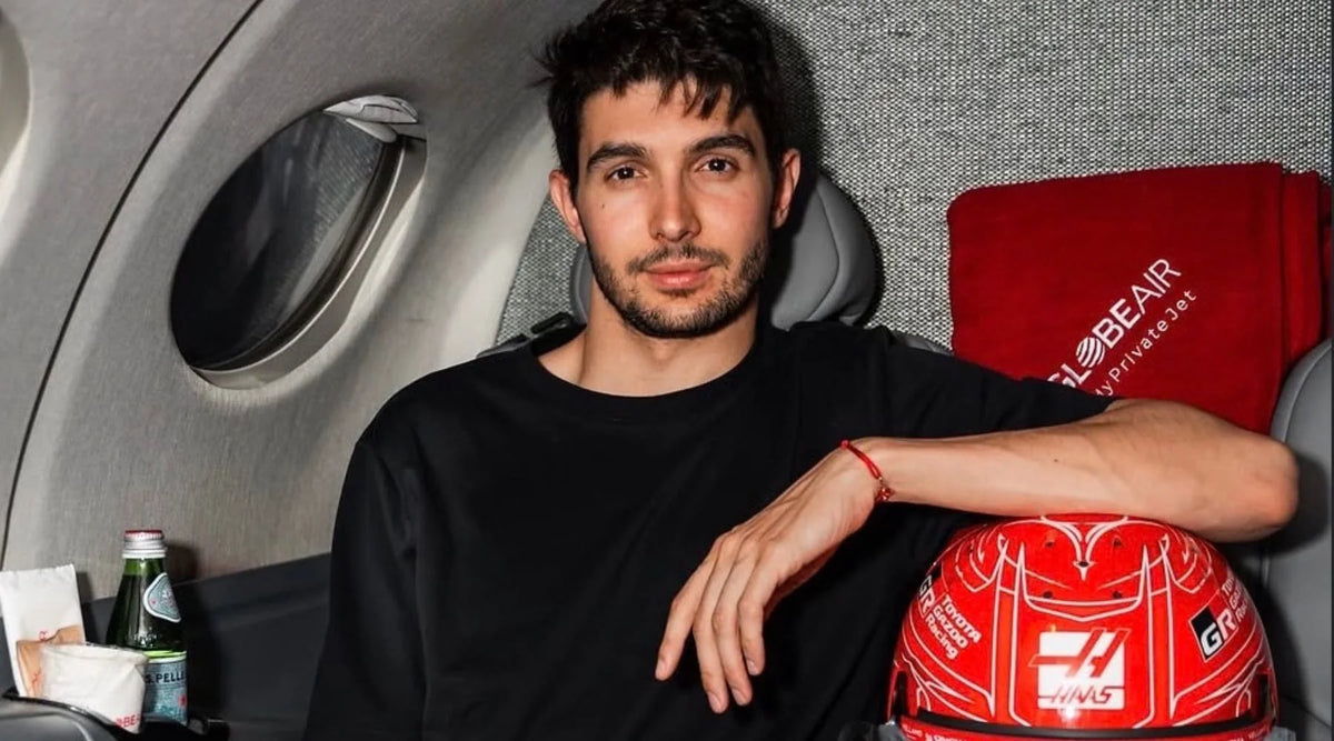 Esteban Ocon 坐在飛機上,身旁放著 Haas 車隊紅色安全帽